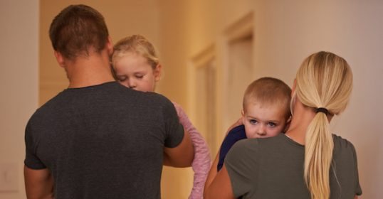 A family walking down a hallway with a baby in their arms.