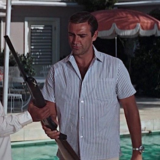 Two chill dudes standing next to a pool with a rifle.