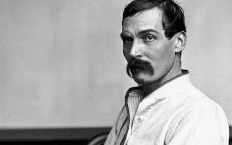 A black and white photo of a man with a mustache.