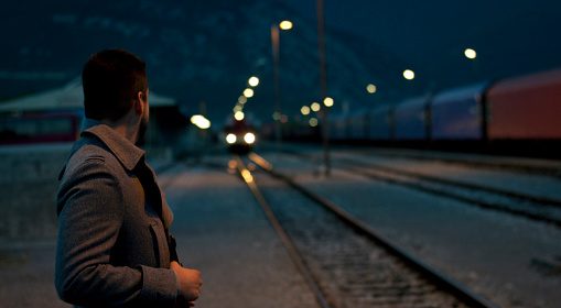 A man standing on a train track at night contemplates his life.