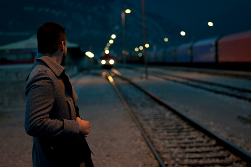 A man standing on a train track at night contemplates his life.