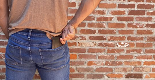 A man is standing next to a brick wall.