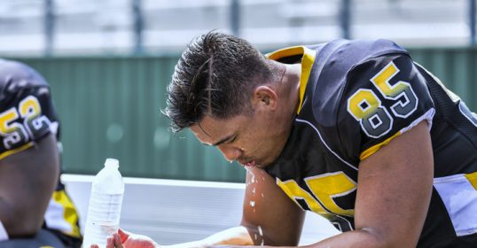 A football player resting on a bench.