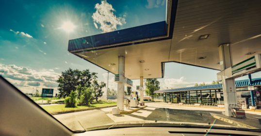 A view of a gas station from the driver's seat while traveling on the road.