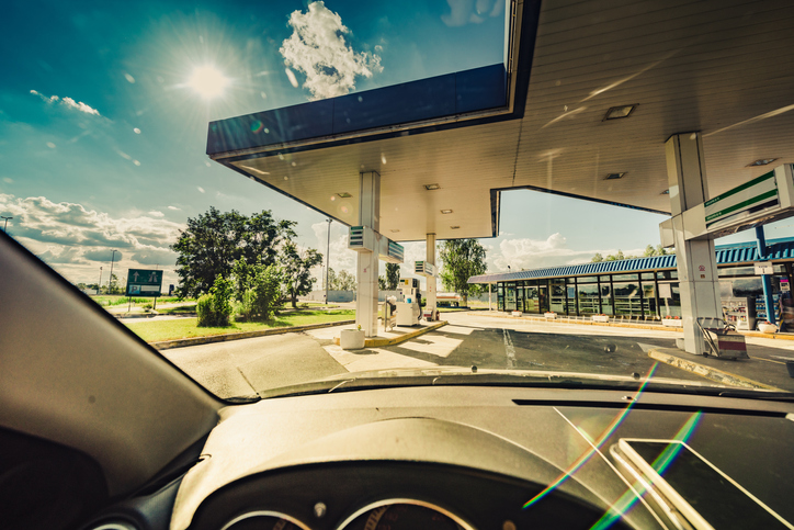 A view of a gas station from the driver's seat while traveling on the road.