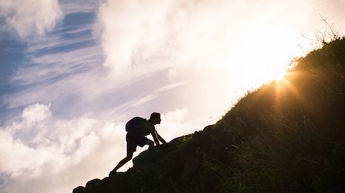 A silhouette of a person climbing a hill in search of self-improvement.