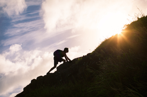 A silhouette of a person climbing a hill in search of self-improvement.