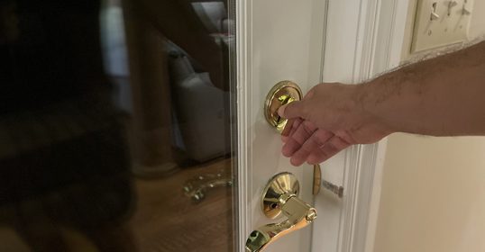 A person performing their security routine by holding a door handle.