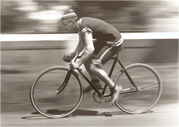 A black and white photo of a man riding a bicycle exudes freedom.