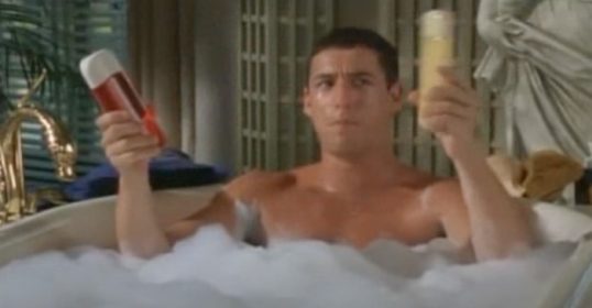 A dude sitting in a bathtub with shampoo.