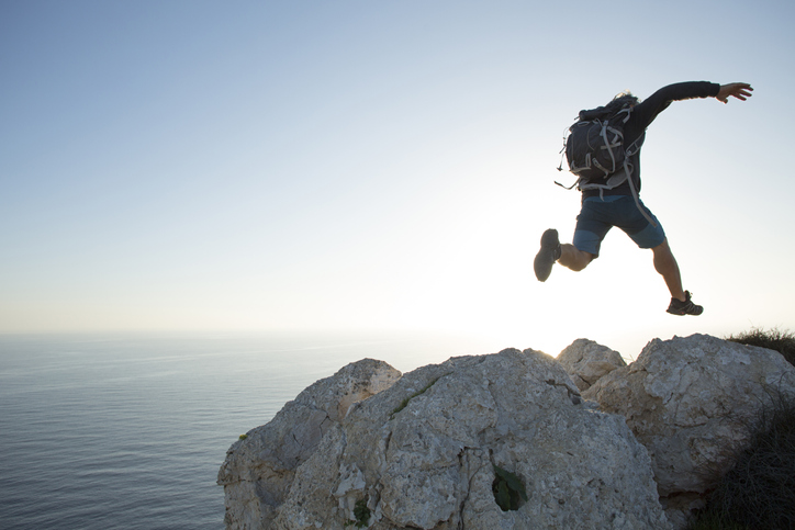 A man jumping off a cliff, showcasing his physical identity.