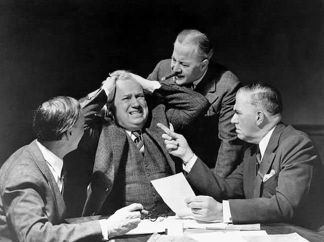 A group of highly skilled men sitting at a table with papers.