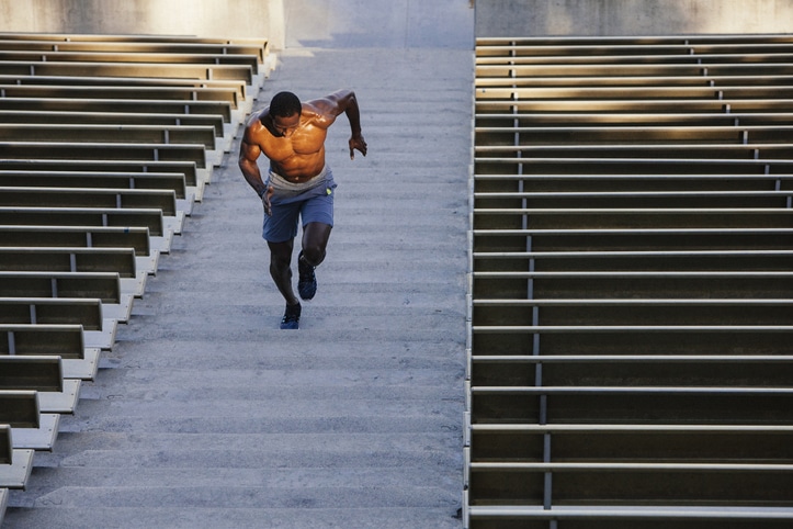 A man conditioning by running up stairs in a stadium to develop his strength.