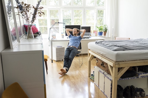 A man lays on his bed in a dorm room, seeking tranquility.