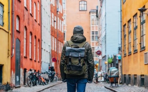 A vagabond with a backpack walking down a cobblestone street in Stockholm, Sweden.