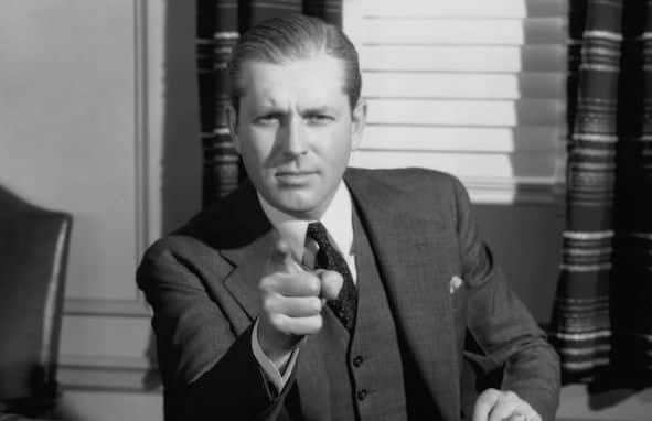 A black-and-white image of an adult in a suit pointing assertively.