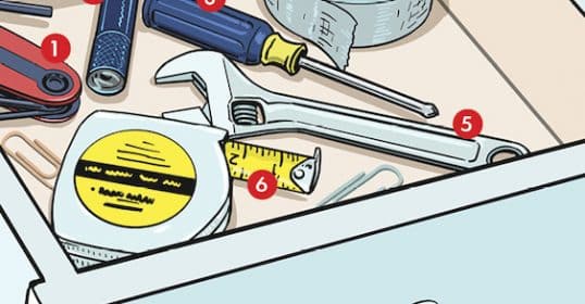 Assorted hand tools and hardware items in a toolbox on a workbench.