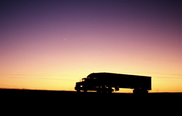 Silhouette of a truck driving at dusk against a gradient sky, embodying the spirit of "Long-Haul Dream".