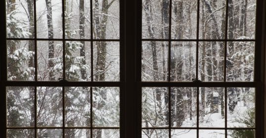 View of a snow-covered forest through a multi-pane window, inspiring one to make New Year's Resolutions.