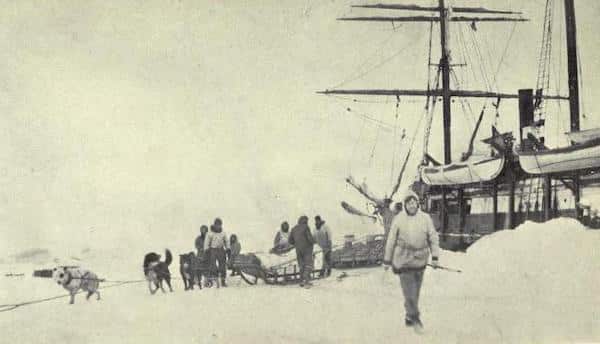 A historical black and white photo of an early Arctic Expedition with people and a sled dog team near a ship encased in ice, featured in Podcast #872 on Leadership Lessons.