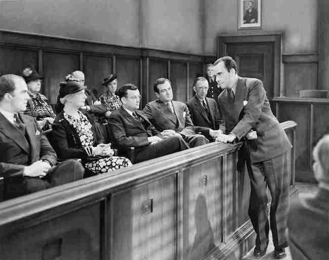 A black-and-white image of a courtroom scene titled "How to Prepare for Jury Duty" where a lawyer is addressing a group of people seated in the jury box.
