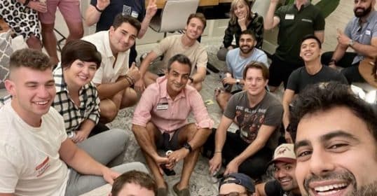 Group of people smiling and posing for a selfie with thumbs up at a Cocktail Party.