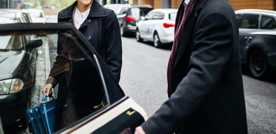 A person exiting a vehicle while another individual holds the door open, reflecting modern etiquette.