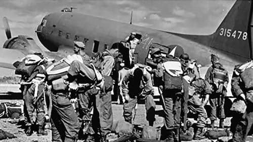 Paratroopers preparing for a jump beside a military aircraft during WWII Pacific Paratroopers.