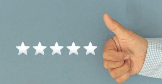 Hand giving a thumbs-up gesture next to five blank stars on a blue background, illustrating how to leave positive reviews.