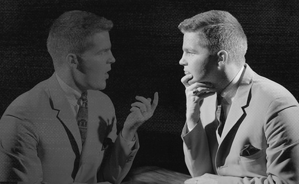 Two identical men engage in a Sunday Firesides conversation on personal development, with one gesturing toward the other.