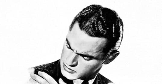 Man in a suit looking thoughtfully at his hand, contemplating how to get rid of dandruff.