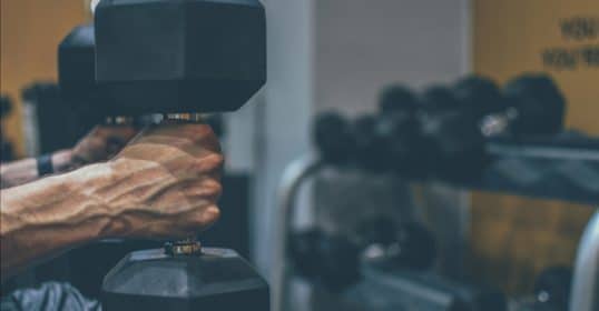 A person showcasing strength by lifting a dumbbell in a gym setting.