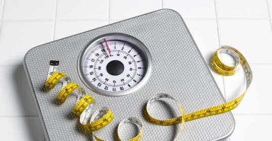 Analog bathroom scale with a measuring tape on top for men looking to lose weight.