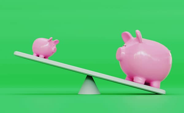Two piggy banks on a seesaw representing financial strategies, with the larger one on the lower side against a green background.