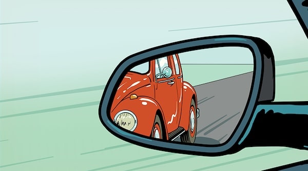 A red vintage car reflected in a vehicle's side mirror, adjusted to eliminate blind spots.