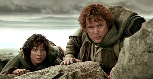 Two individuals, embodying Hobbit virtues, peering over a rocky outcrop with apprehensive expressions.