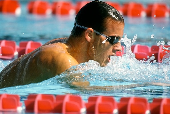 A man swimming in a pool with goggles on, exemplifying the mundanity of excellence.