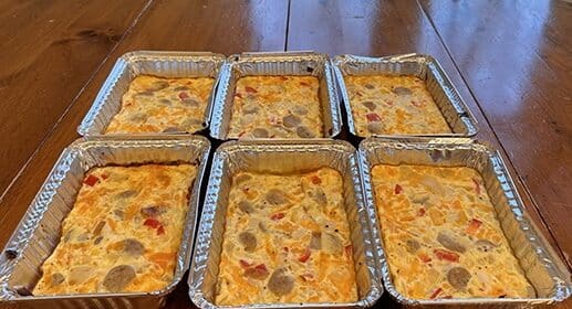 A stack of cheap aluminum pans with high-protein breakfast casseroles in them.
