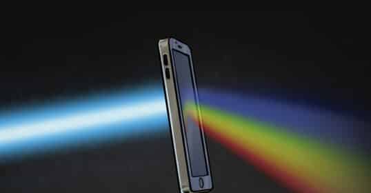 Smartphone emitting colorful light spectrum on a dark background, illustrating communication or signal concept.