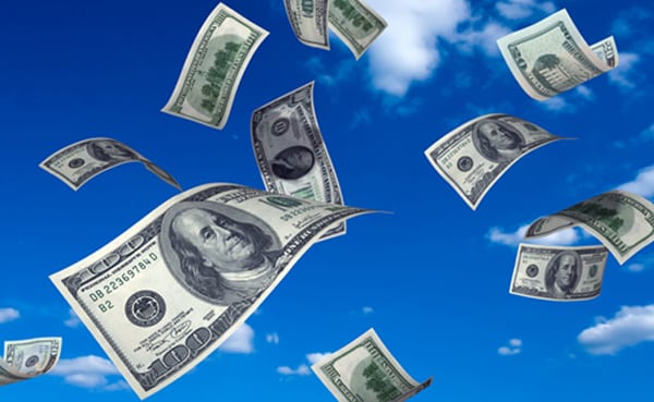 U.S. hundred dollar bills fluttering against a clear blue sky with white clouds symbolize a sudden financial windfall.