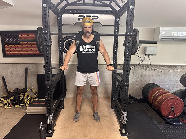 a man standing in a gym performing hatfield squat