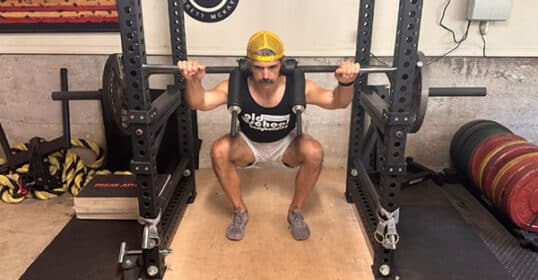 a man squatting with weights on a metal rack