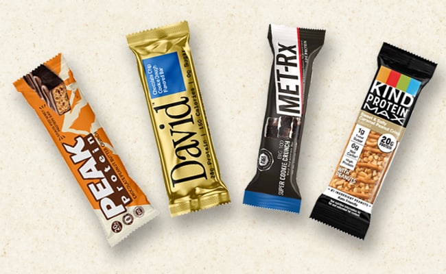 Four of the best protein bars—Peak Protein, David Protein Bar, MET-Rx, and KIND Protein—are artfully displayed against a neutral background, showcasing their appeal as top choices for protein supplements.