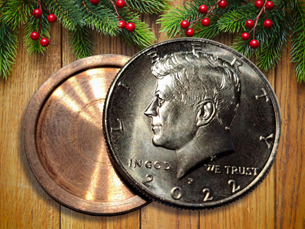 A 2022 Kennedy half dollar coin and a round brass container, perfect as stocking stuffers for men, are placed on a wooden surface with pine branches and red berries at the top.
