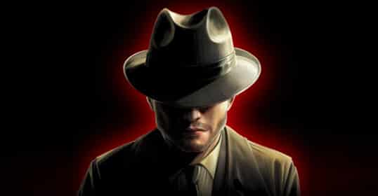 Person in a suit and hat with face obscured, illuminated by a red halo effect against a dark background.