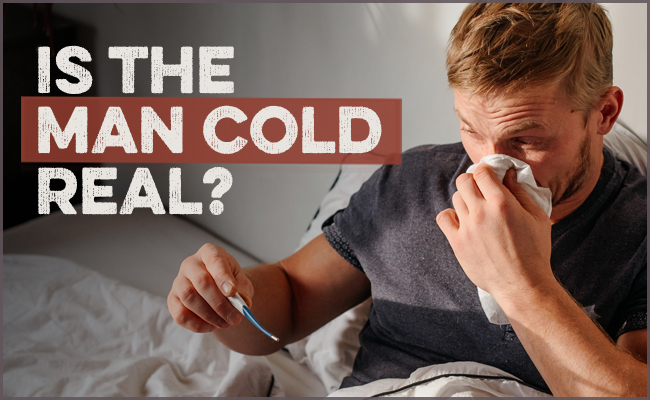 A man sitting in bed, clutching a thermometer and tissues, appears to be suffering from the dreaded "man flu." The text reads, "Is the man flu real?.