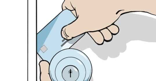 A hand demonstrates how to open a locked door by sliding a credit card between the door and the frame near the lock.