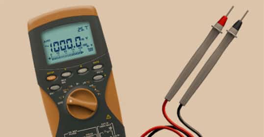 A digital multimeter displaying a voltage reading, with attached red and black probes lying next to the device on a beige background—ideal for anyone seeking a clear visual in a multimeter tutorial or learning how to use a multimeter.