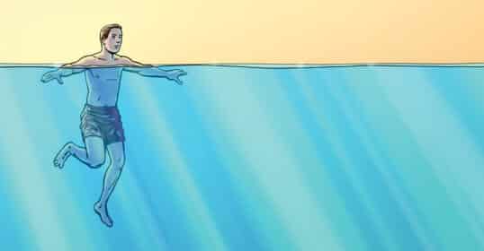 A person wearing swim trunks is treading water in a large body of water, enjoying an aquatic fitness session with arms outstretched as sunlight streams through the surface.