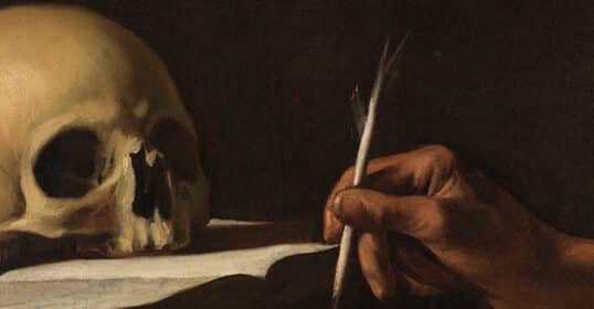 A human skull rests on a surface beside a hand holding a quill pen, poised to write on a piece of paper—an evocative scene for those who seek powerful quotes or thought-provoking quotes about death.